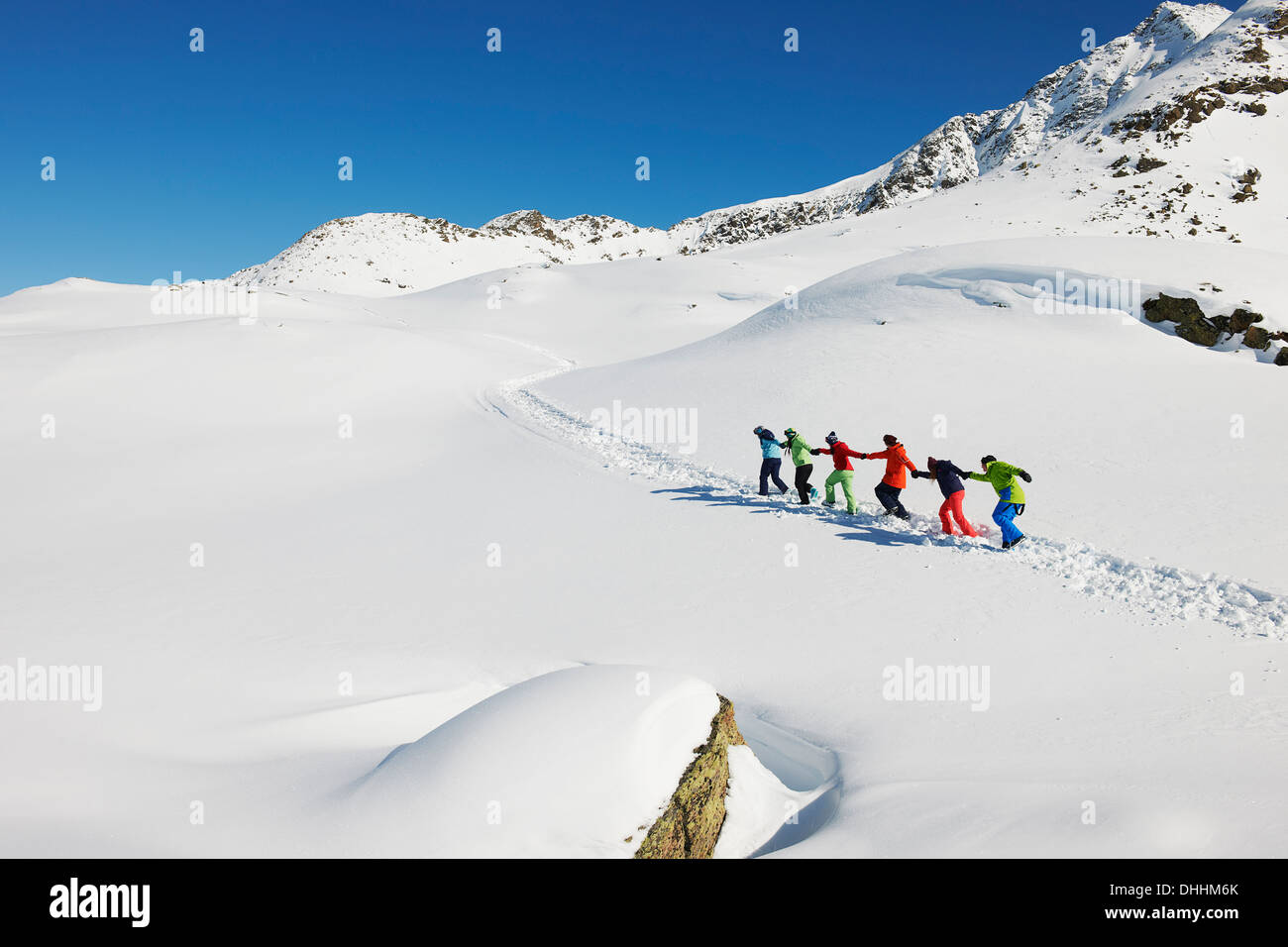 Freunde ziehen einander bergauf im Schnee, Kühtai, Österreich Stockfoto