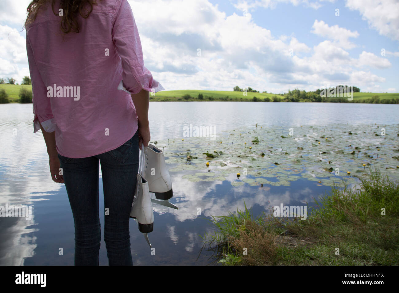 Teenager-Mädchen neben See hält Schlittschuhe Stockfoto