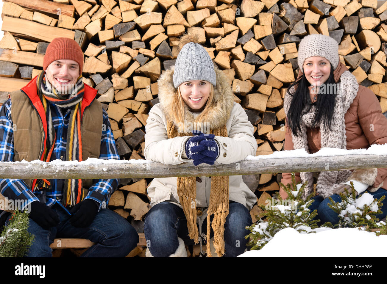 Junge Leute sitzen außen Winter Kleidung Holzscheite im Hintergrund Stockfoto