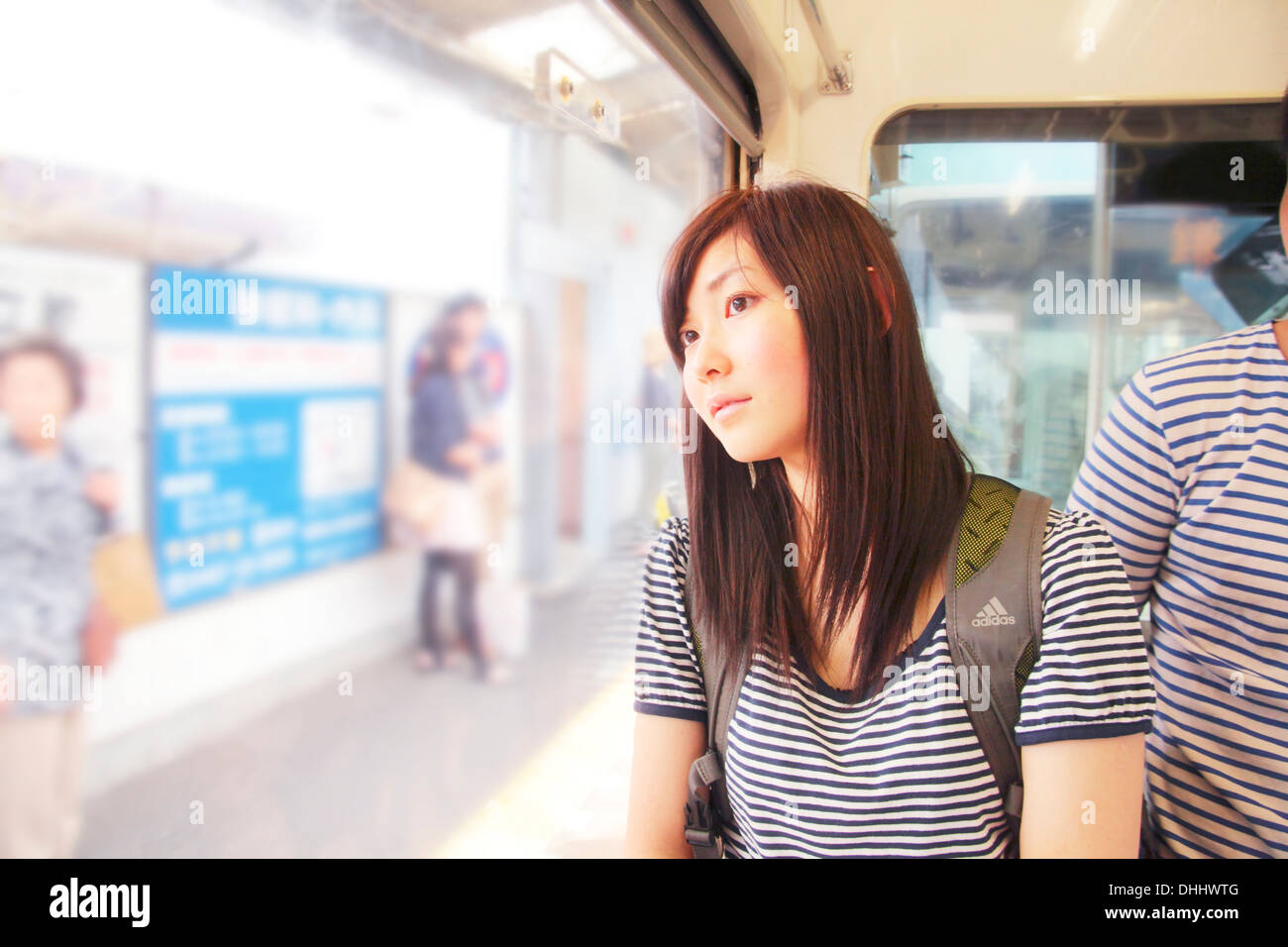 Junge Frau am Bahnhof, Blick durch Fenster Stockfoto