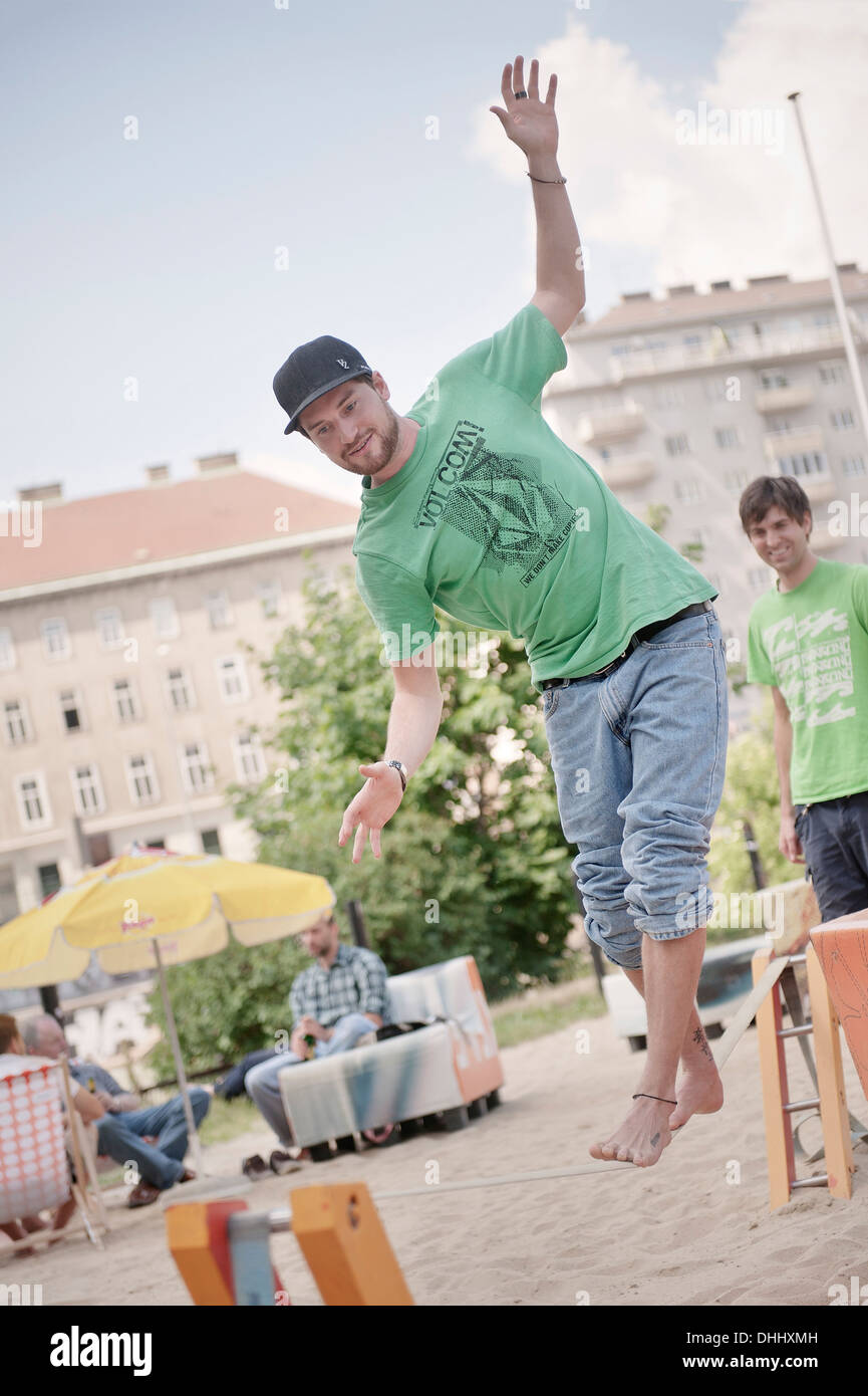 Junger Mann Balaning auf einer Slackline am Donau-Strand, Wien, Österreich, Europa Stockfoto