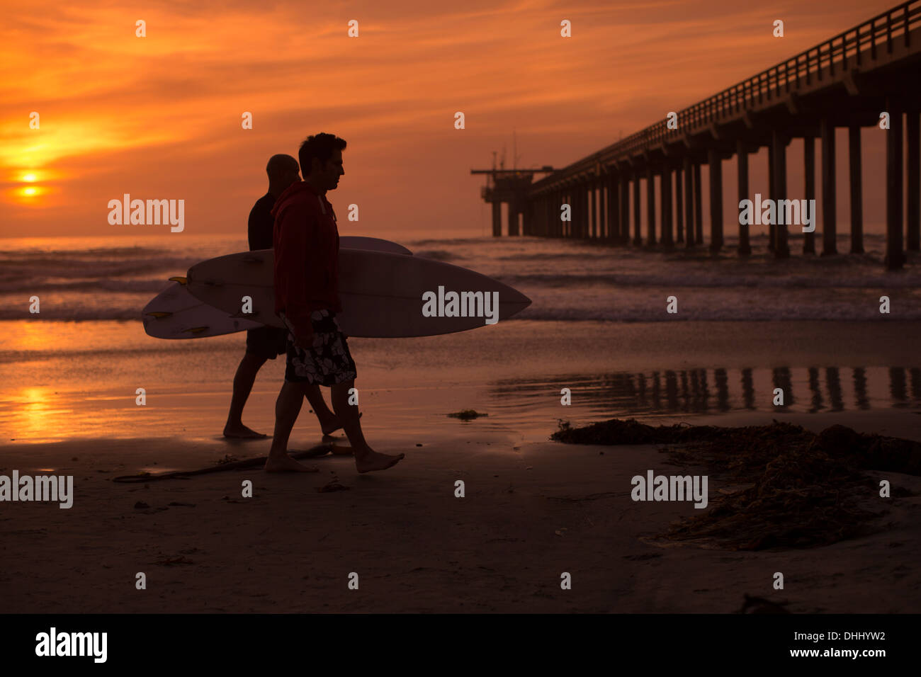 Zwei Männer tragen Surfbretter am Strand Stockfoto