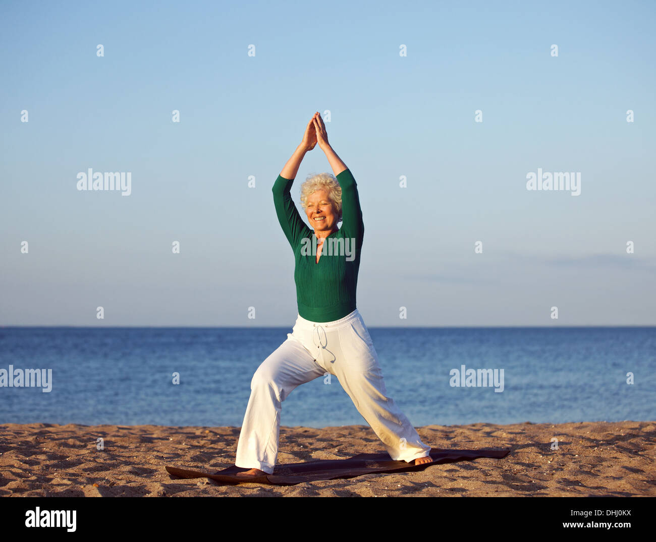 Ältere Frau Strand Hintergrund dehnen. Reife kaukasischen Frau Ausübung Morgen am Sandstrand Stockfoto