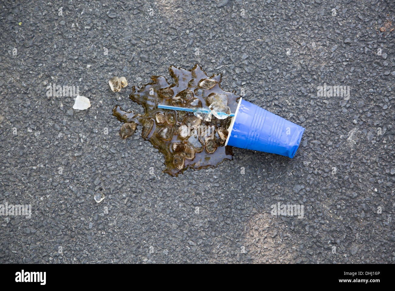 Verschüttete Softdrink mit Kunststoff Tasse und Eiswürfeln auf Asphalt Stockfoto