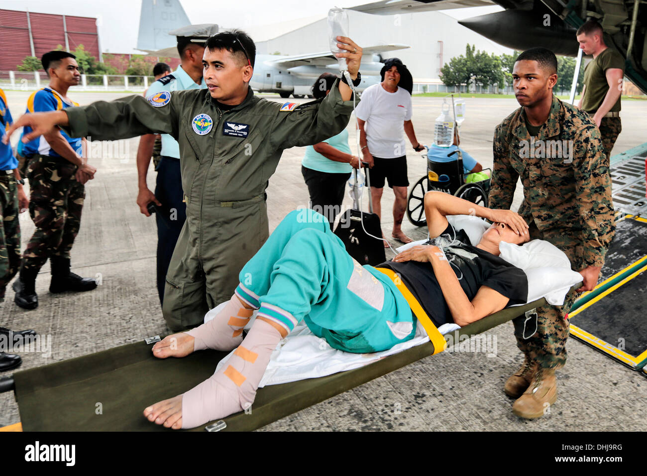 US-Marines tragen eine verletzte Filipina Frau von der Rückseite des KC-130J Super Hercules Transportflugzeug auf Villamor Air Base 11. November 2013 in Manila, Philippinen. Die USA trat Hilfsmaßnahmen nach den Verwüstungen durch Super Taifun Haiyan, die geglaubt wird, um über die philippinischen Inseln 10.000 Menschen getötet wurden. Stockfoto