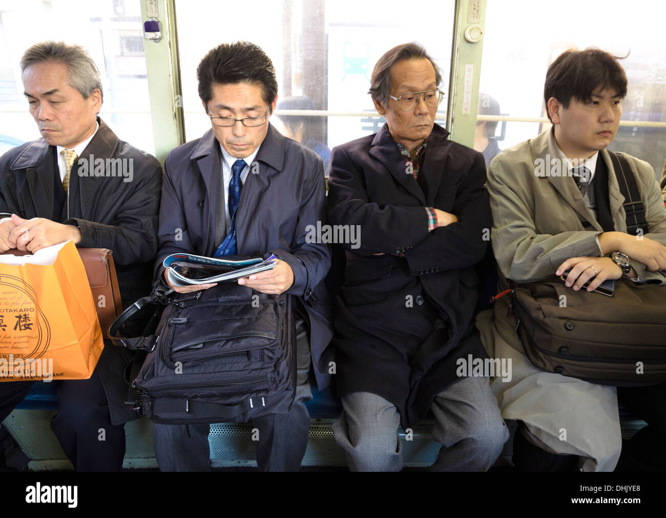 Unglückliche männliche Arbeitnehmer: asiatische Salaryman Pendler, nach Hause mit der Straßenbahn (Tram). Stockfoto