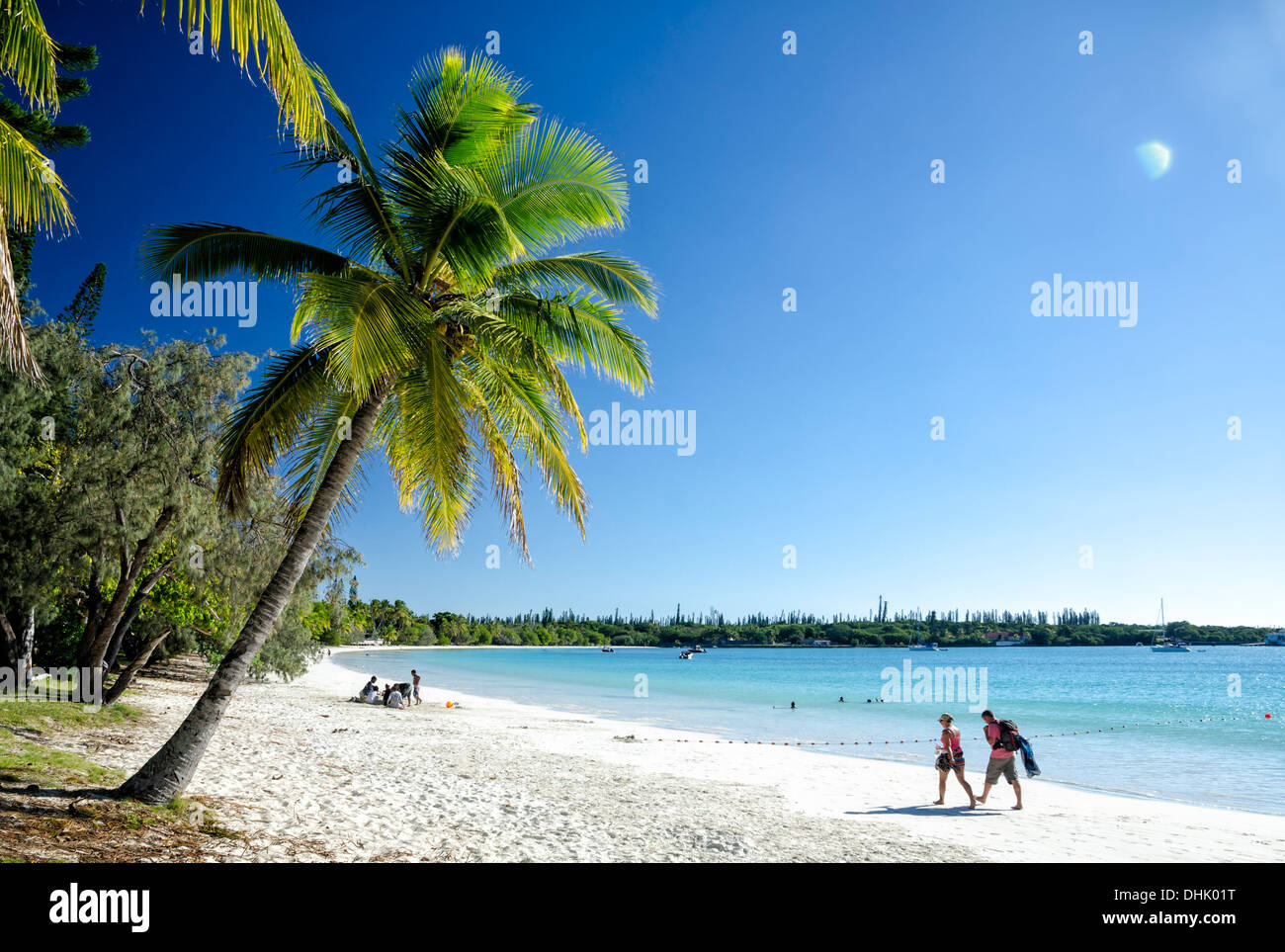 Menschen zu Fuß auf den perfekten weißen Sand von einem tropischen Strand, unter Palmen und neben dem reinen Blau des Meeres Stockfoto