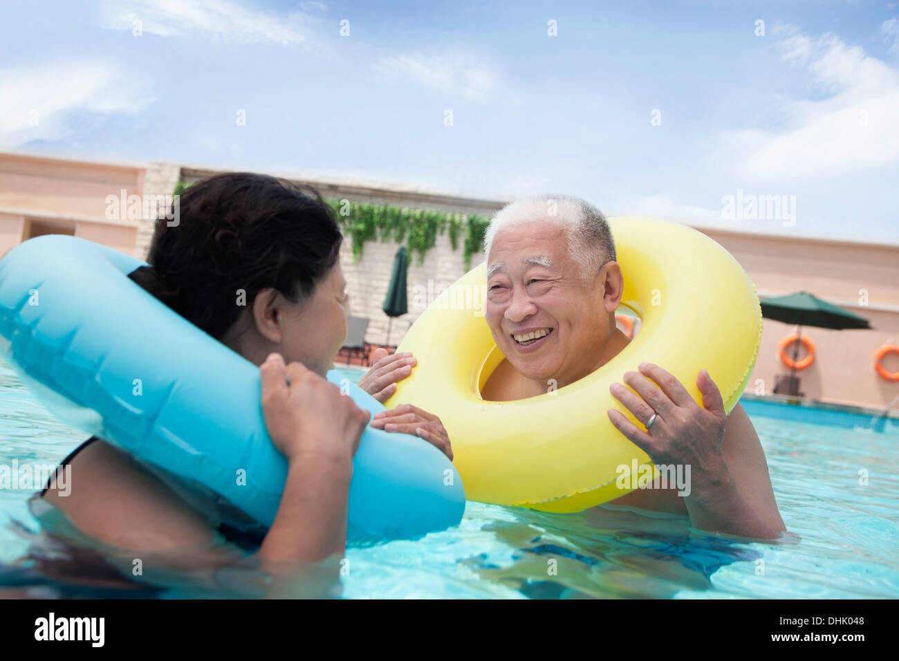 Älteres paar lächelnd und entspannen im Pool mit aufblasbaren Schläuchen Stockfoto