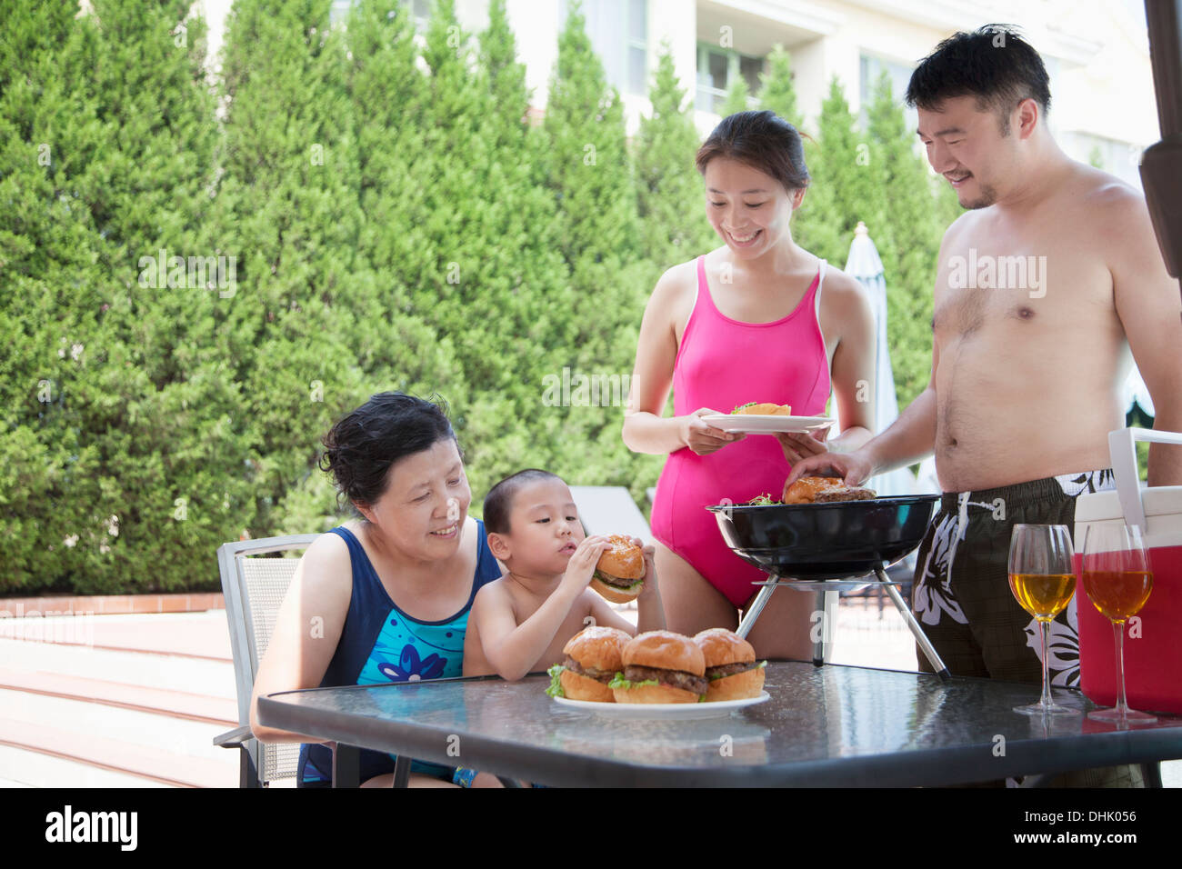 Lächelnd generationenübergreifenden Familie grillen am Pool im Urlaub Stockfoto
