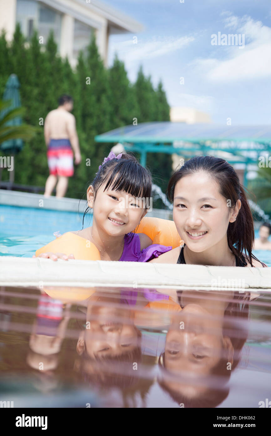Porträt der Mutter und Tochter im Pool am Rand, Blick in die Kamera Lächeln Stockfoto