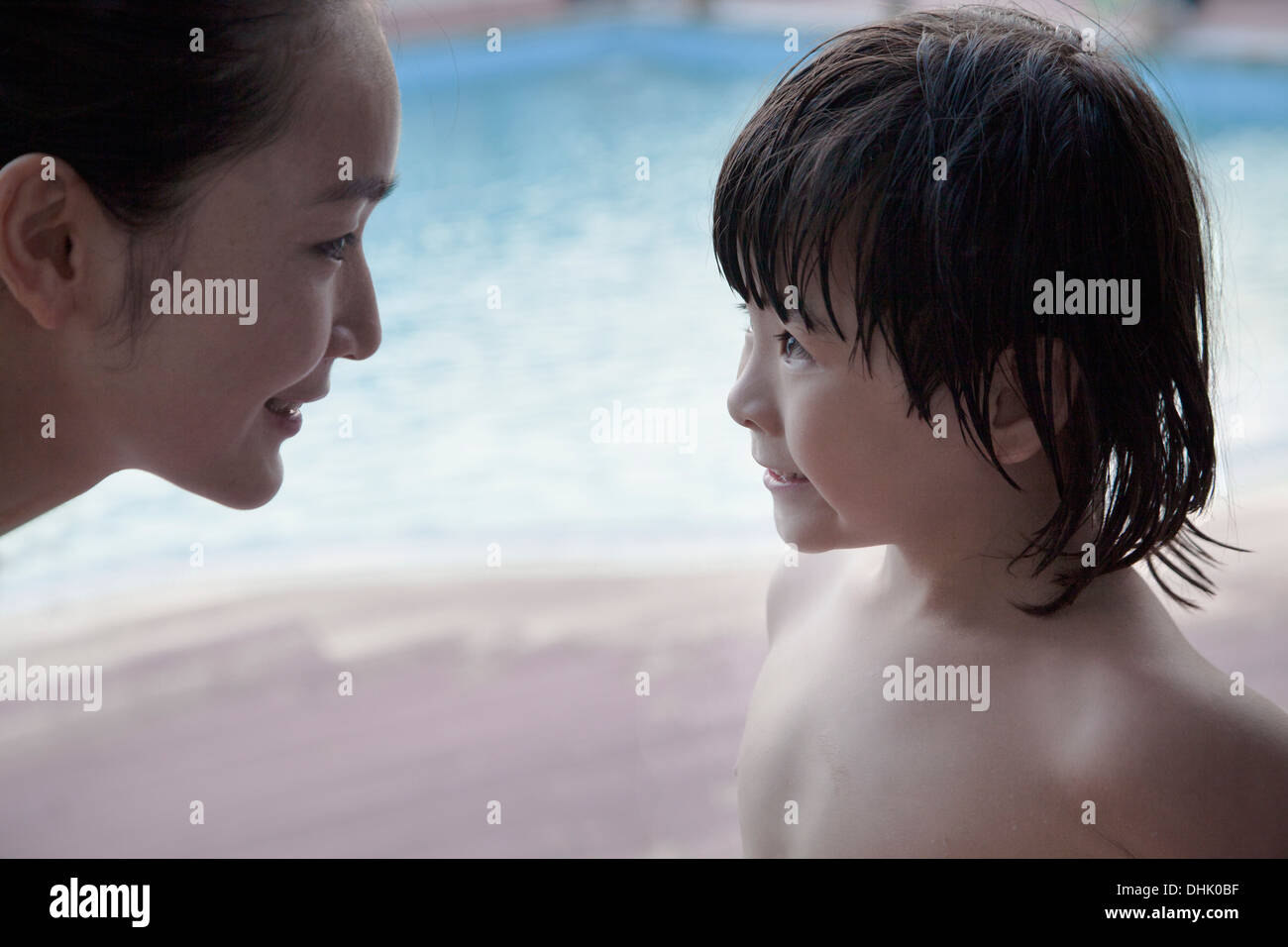Lächelnde Mutter und Sohn von Angesicht zu Angesicht am Pool Stockfoto