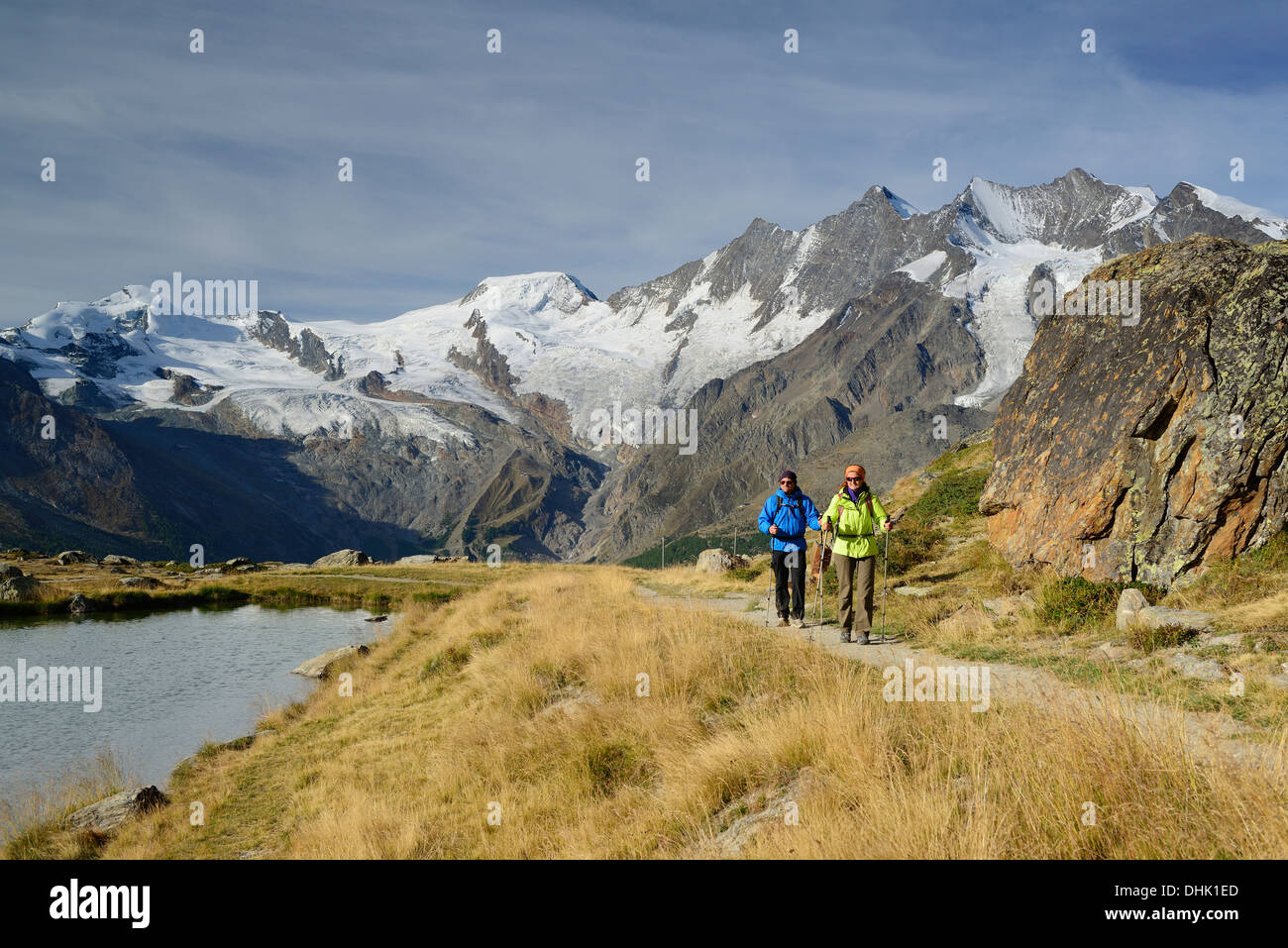 Frau und Mann in der Nähe von einem Bergsee mit Blick zur Mischabel Range mit Allalinhorn, Alphubel, Taeschhorn, Dom und Lenzspitz Wandern Stockfoto