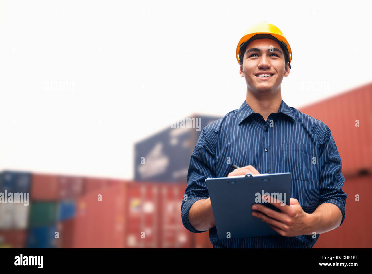 Lächelnde jungen Ingenieur in schützende Arbeitskleidung in einen Frachthafen Prüfung Fracht Stockfoto