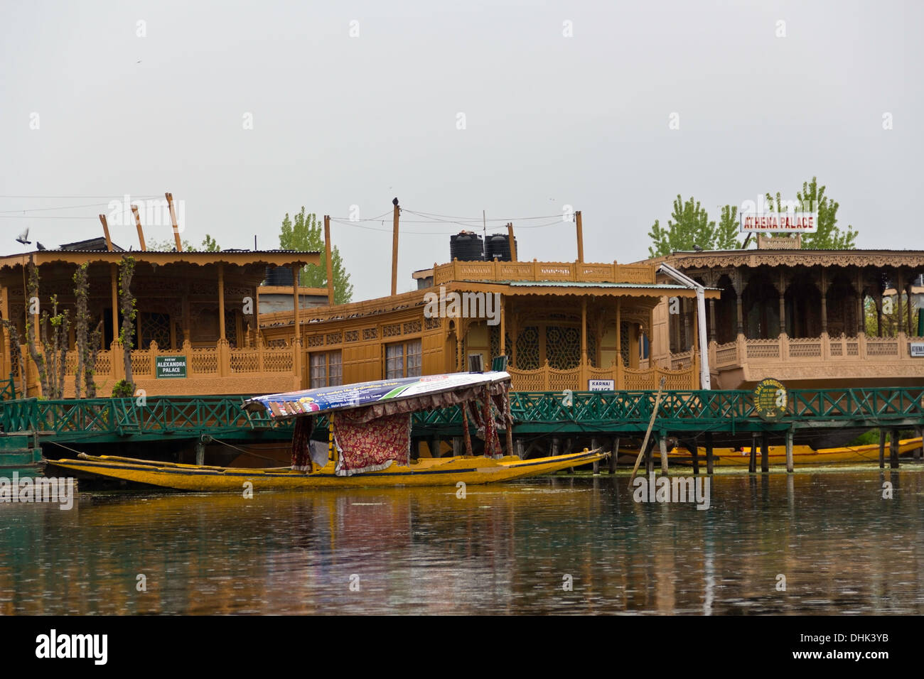 Shikara gebunden, Hausboote in der Dal-See in Srinagar in Kaschmir, mit 3 großen Hausbooten am Ufer des Sees. Stockfoto