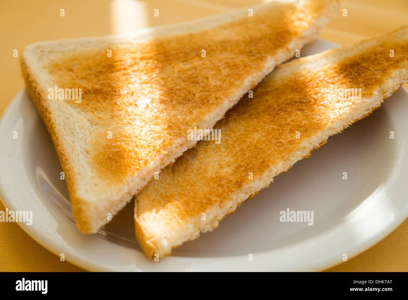 Zwei Scheiben weißen Toast sitzt auf einem weißen Teller mit Sonnenstrahlen über sie. Stockfoto