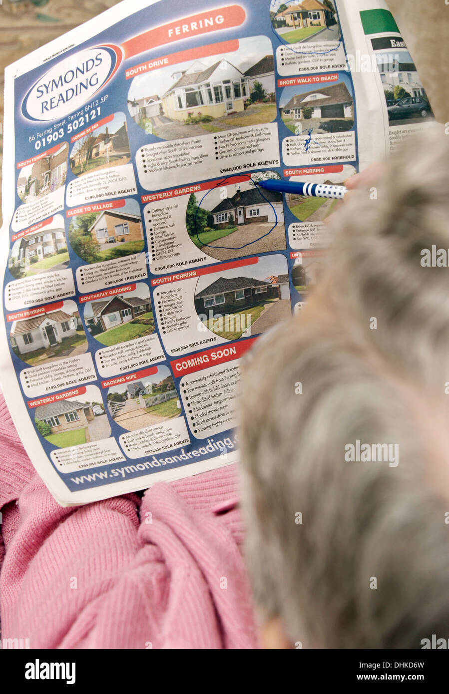 Ältere Frau betrachten Eigenschaften auf den Eigenschaftenseiten in einer Lokalzeitung & Kennzeichnung aus etwas interessantes Stockfoto