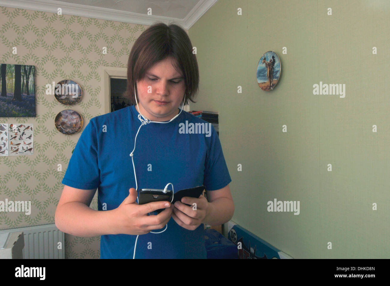 Teenager mit einem Handy in seinem Schlafzimmer. Stockfoto