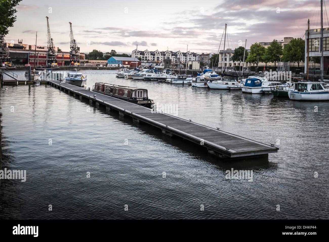 Yachten, Kräne und Vergnügungsschiff vertäut am schwimmenden Steg in der Marina in Bristol Docks, Avon, England bei Sonnenuntergang. Stockfoto