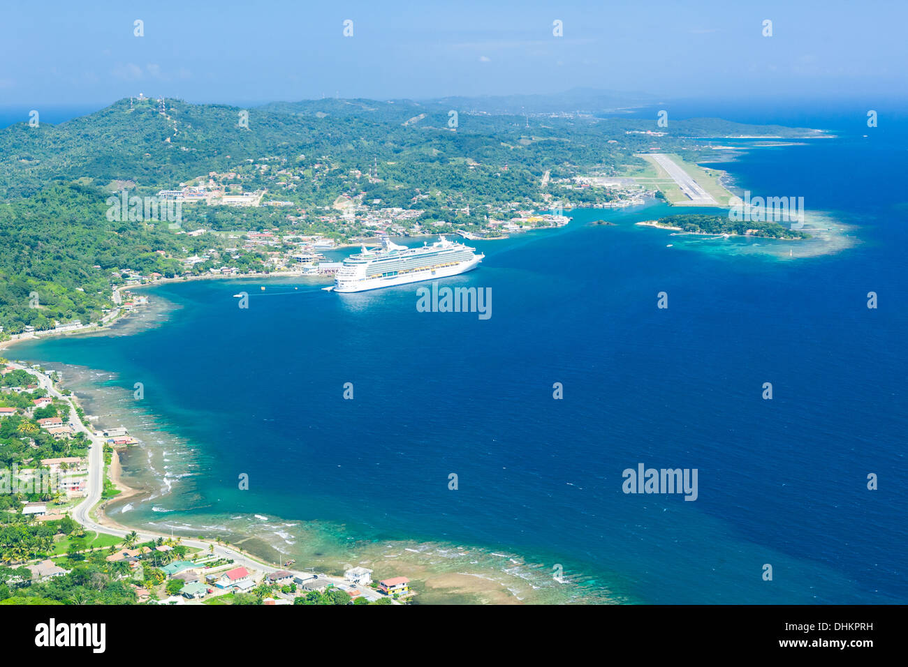 Luftbild des Cruieship am Hafen von Roatan mit Flughafen-Landebahn im Hintergrund verankert. Insel Roatan, Honduras Stockfoto
