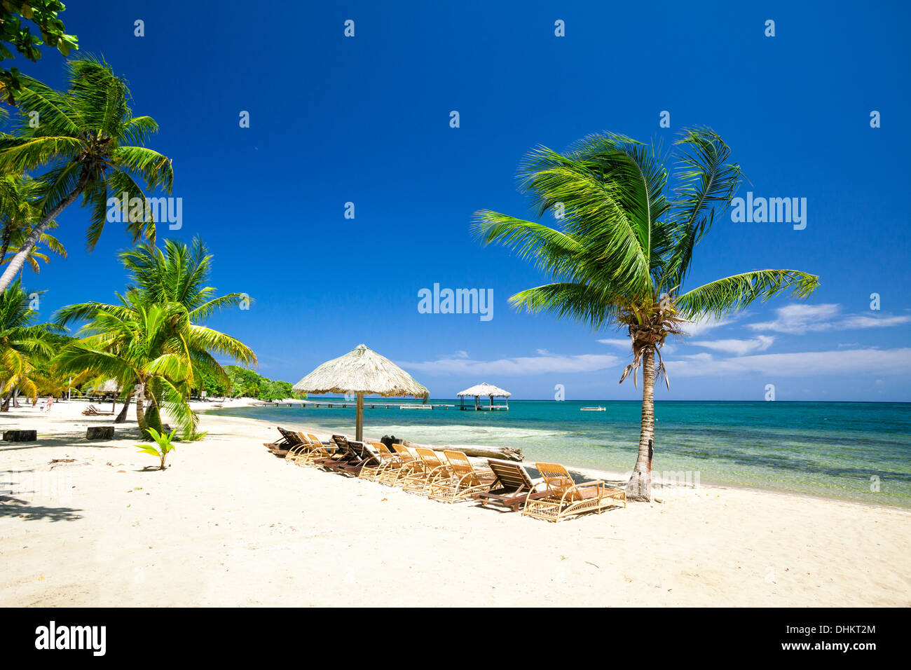 Stühle aufgereiht neben einem Strohdach Palapa an einem karibischen Strand Stockfoto