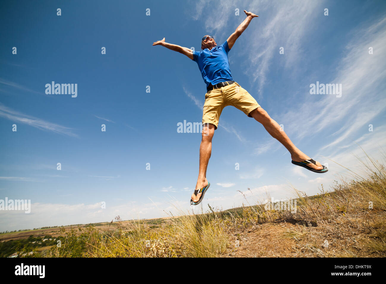 Glücklicher Mann springen, blauen Himmel im Hintergrund, Weitwinkel Stockfoto