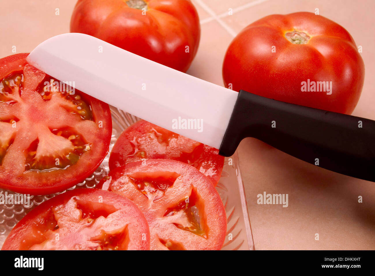 Garten frische Tomaten werden in Scheiben geschnitten, mit einem sehr scharfen Messer Keramik. Stockfoto