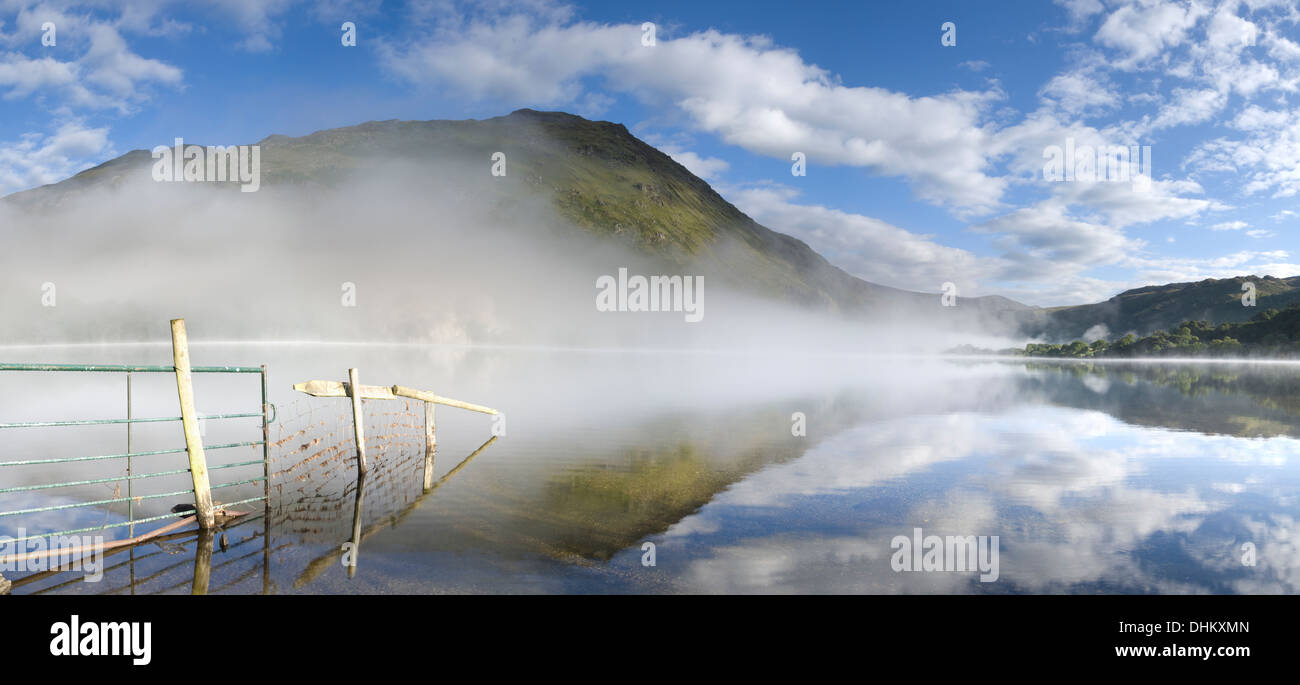 Panarama ein Zaun und Reflexion in Llyn Gwynant gehen. Der Nebel steigt über dem See teilweise verdeckt Gallt y Wenallt Stockfoto