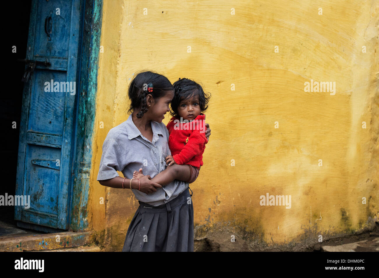 Indische Mädchen hält ihre Babyschwester an ihrer Hüfte in einem indischen Dorf. Andhra Pradesh, Indien Stockfoto