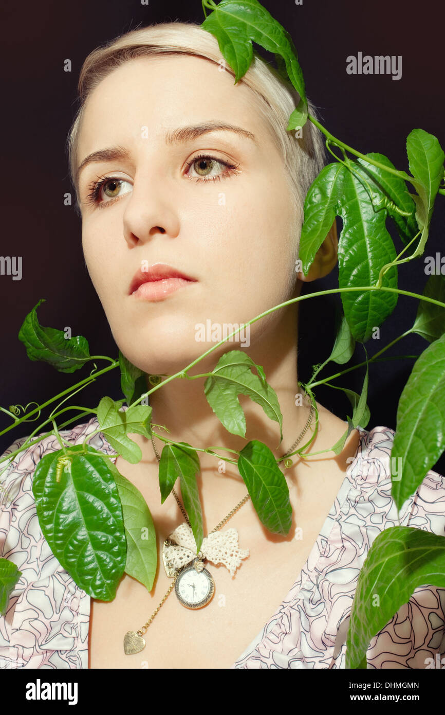 Porträt einer jungen Frau mit einer Passionsfrucht Pflanze auf einem schwarzen Hintergrund Stockfoto