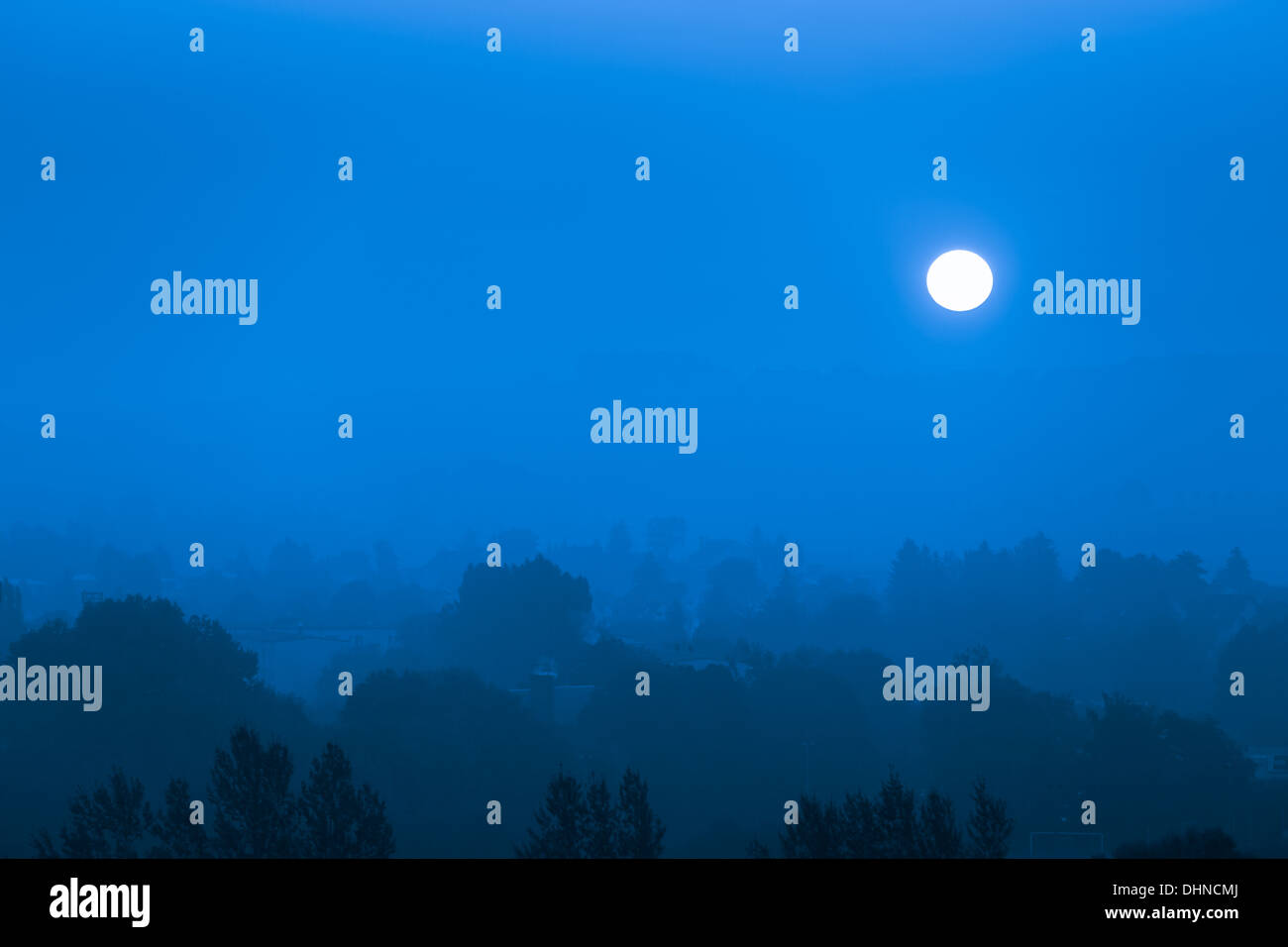 Mondaufgang über der blauen Nebel Stadt Stockfoto