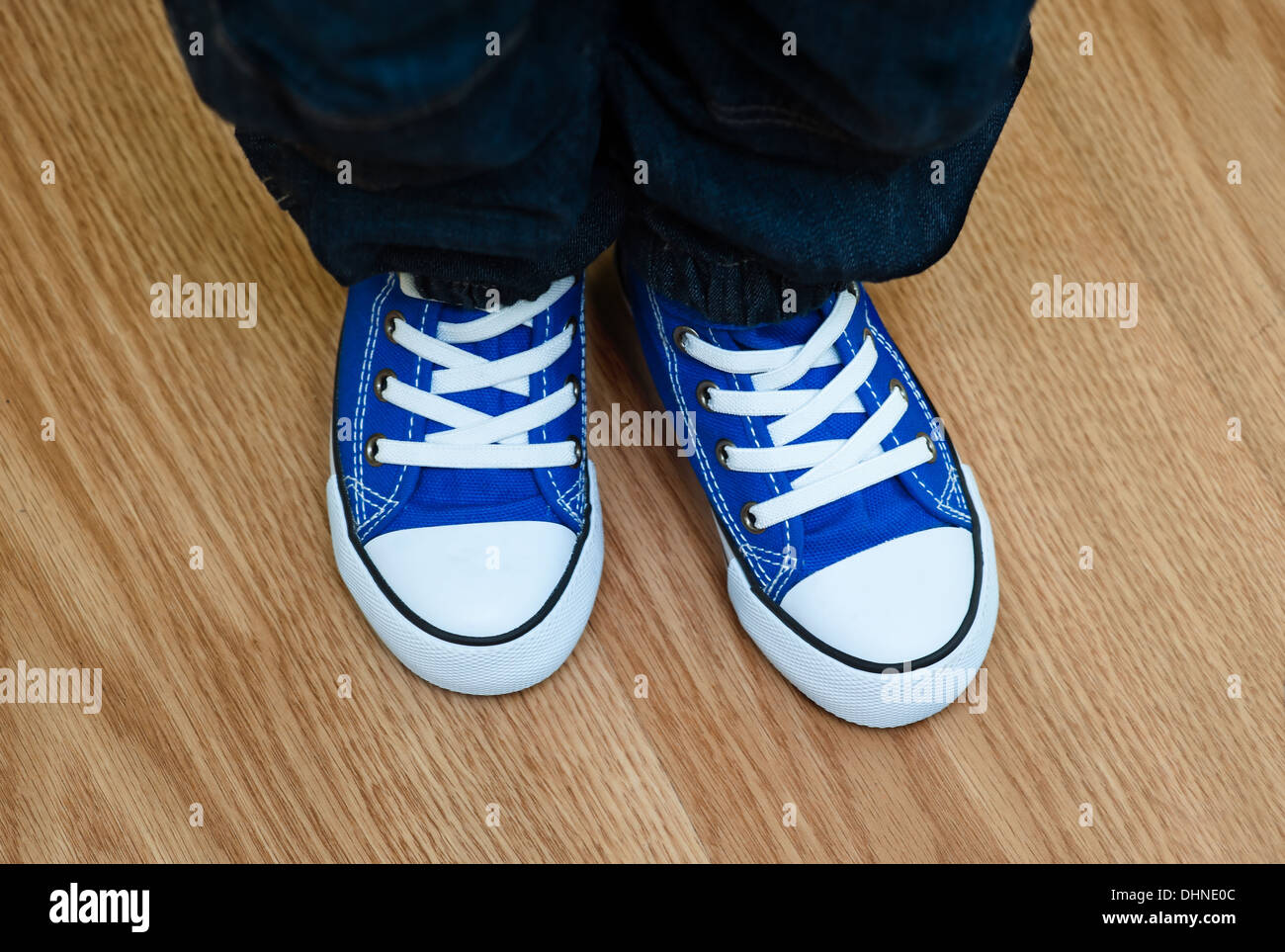 Beine eines kleinen Jungen in Turnschuhen auf dem Boden zu Hause Stockfoto