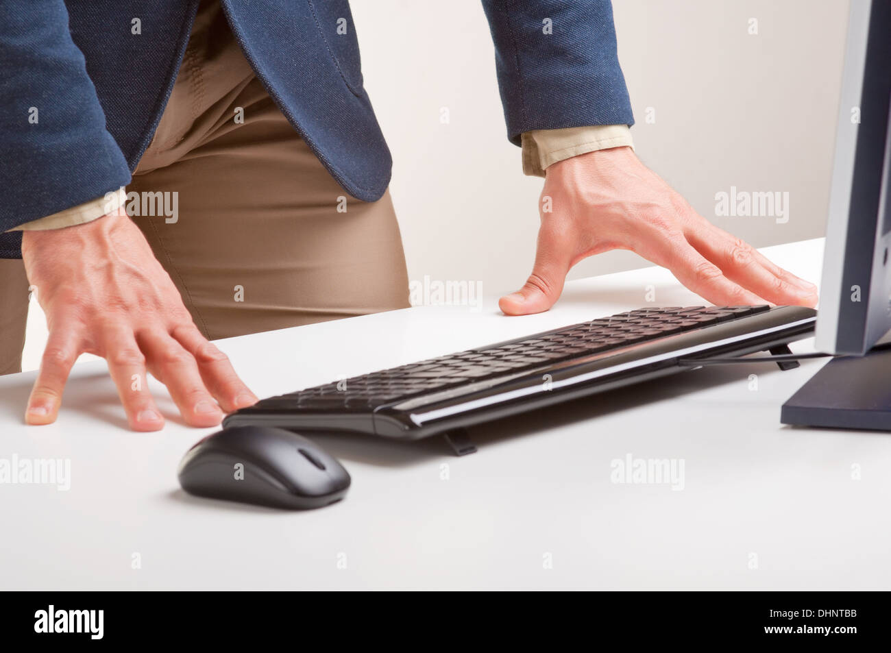 Mann stehen und blickte auf einen Computerbildschirm mit seinen Händen auf dem Schreibtisch Stockfoto