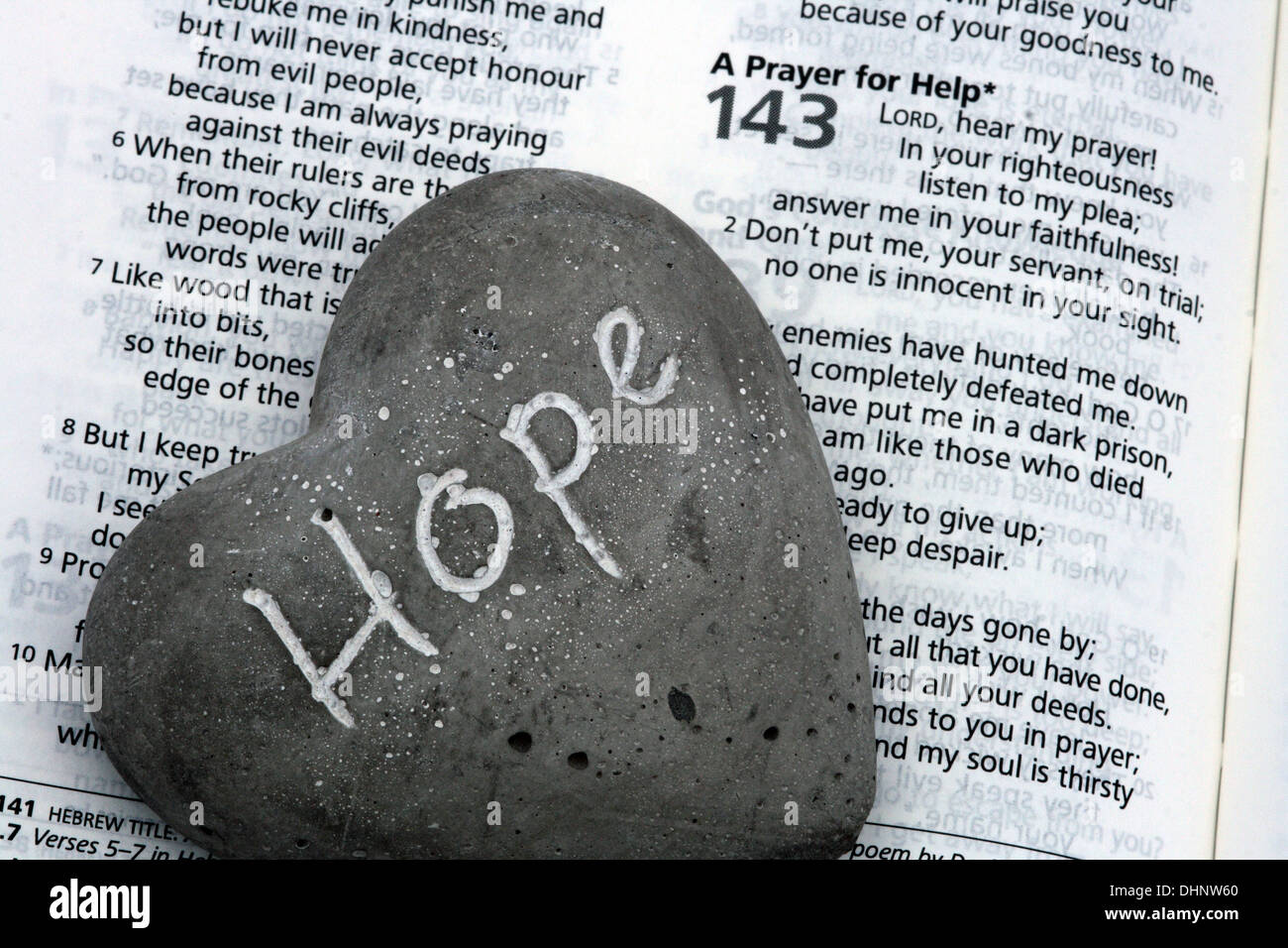 Das Wort "Hoffnung" wurde auf eine kleine steinerne Herz gemalt. Das Herz ruht auf einer Seite der Bibel. Stockfoto
