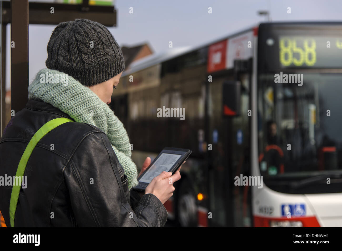 junge Frau liest ein eBook an einer Bushaltestelle Stockfoto