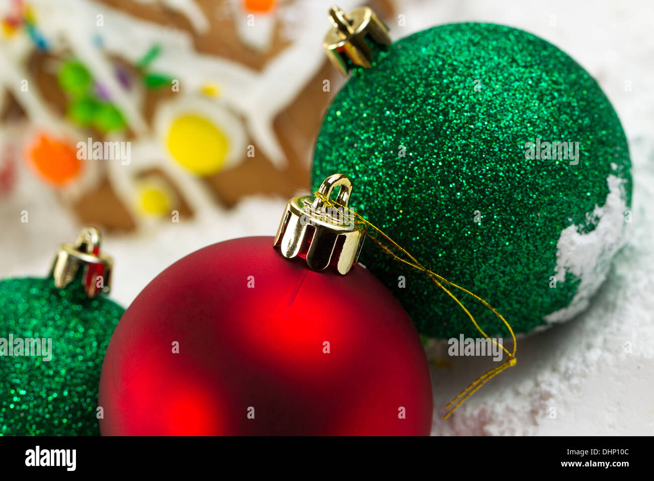 Closeup horizontale Foto von oben der Rote Christbaumkugel mit Lebkuchenhäuser, umgeben von Pulverschnee im Hintergrund Stockfoto