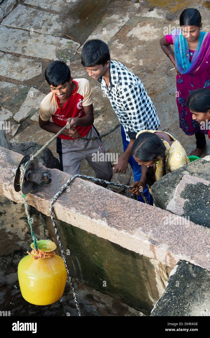 Indische Mädchen und jungen zeichnen Wasser aus einem Brunnen in einem indischen Dorf Straße. Andhra Pradesh, Indien Stockfoto