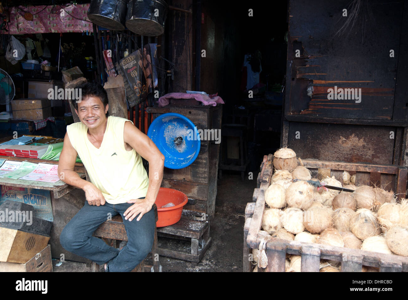 Ein Stall Besitzer sitzt durch seine Produkte auf dem Marktplatz in Davao Stockfoto