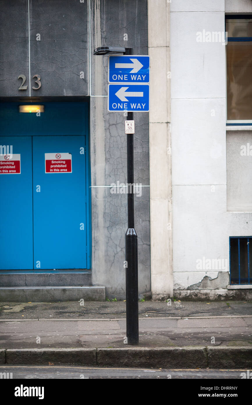 Zwei unidirektionale Verkehrszeichen montiert übereinander aber beide zeigen in entgegengesetzte Richtungen. London, UK. Stockfoto