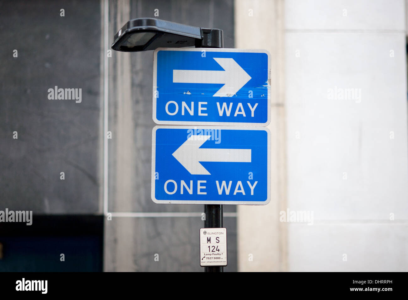 Zwei unidirektionale Verkehrszeichen montiert übereinander aber beide zeigen in entgegengesetzte Richtungen. London, UK. Stockfoto