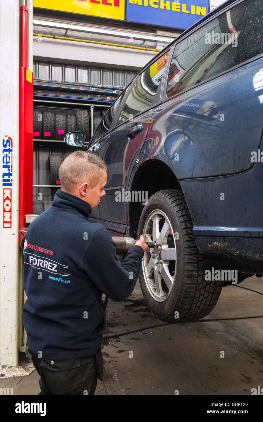 Kfz-Mechaniker ändern Sommerreifen und Winterreifen auf Rädern des Fahrzeugs auf Rampe in der Montagehalle von Reifenzentrum Montage Stockfoto