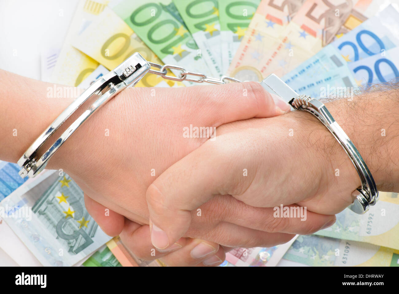 Händeschütteln mit Handschellen mit Geld im Hintergrund Stockfoto