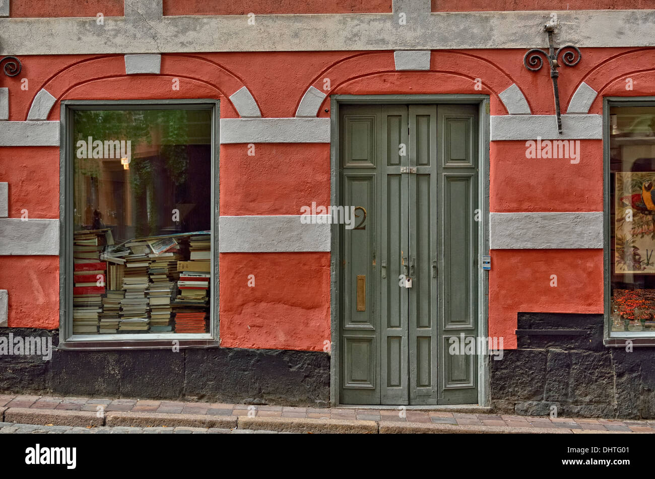 Die Buchliebhaberin Gamla Stan, Stockholm, Schweden. Bücherstapel, eingerahmt in einem farbenfrohen Gebäude in der Altstadt, ein touristischer Anziehungspunkt. Stockfoto