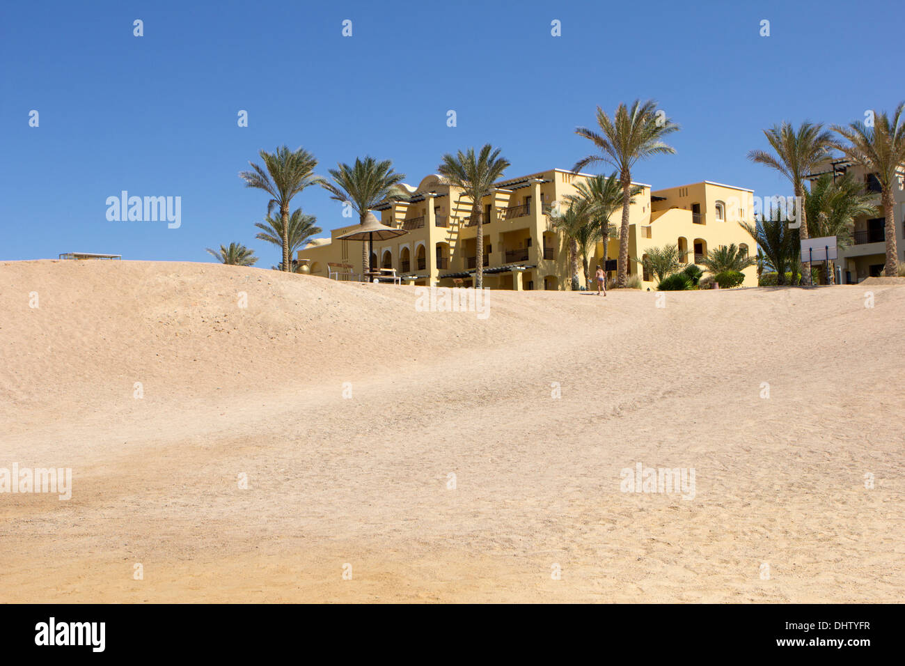 Gebäude am Ende einer Wüste mit Palmen Stockfoto