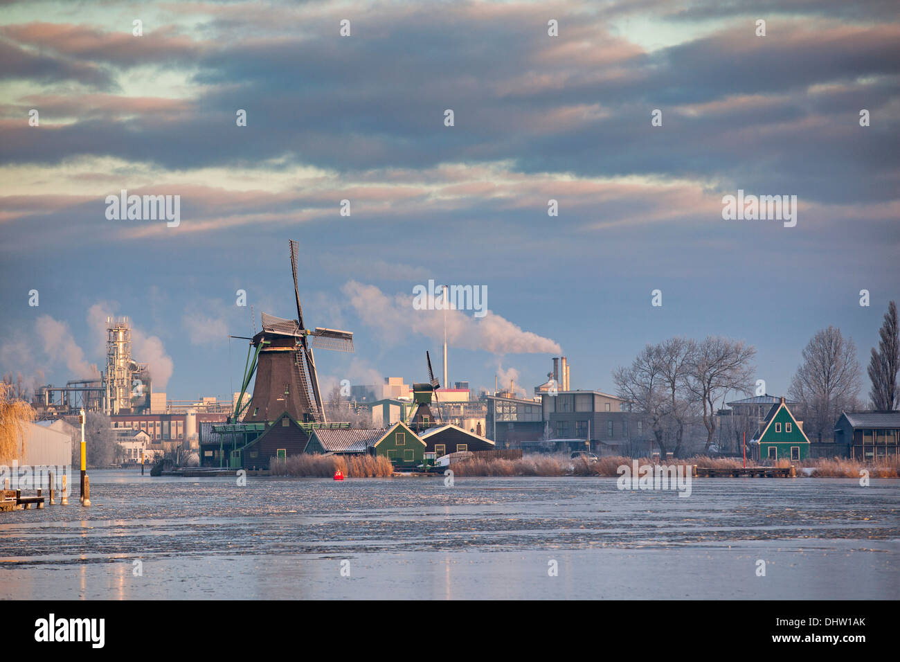 Niederlande, Zaanse Schans in der Nähe von Zaandam, Windmühle vor modernen Industrie. Winter Stockfoto