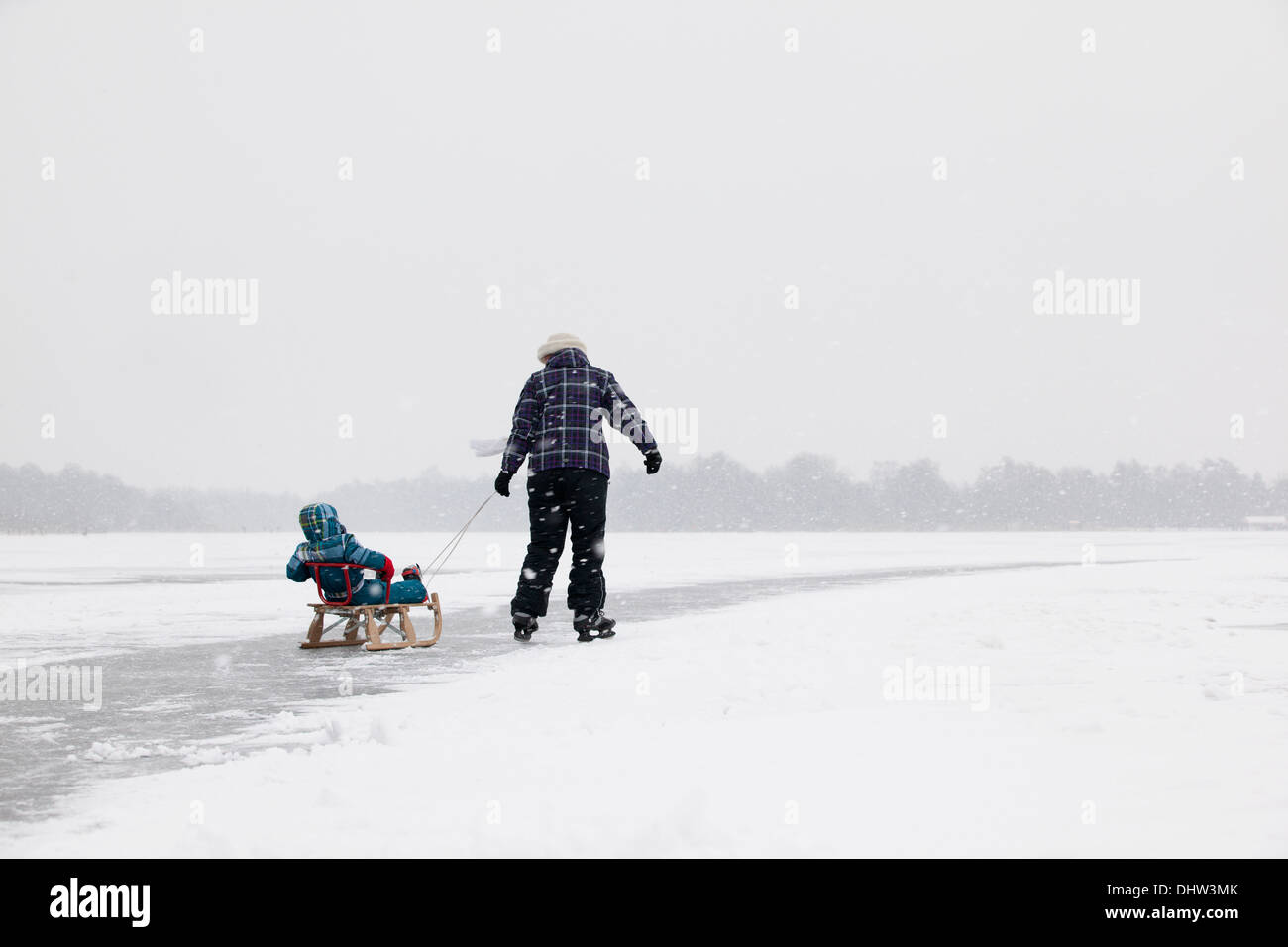 Niederlande, Loosdrecht, Seen genannt Loosdrechtse Plassen. Winter. Mutter mit Kind auf Schlitten Eislaufen Stockfoto