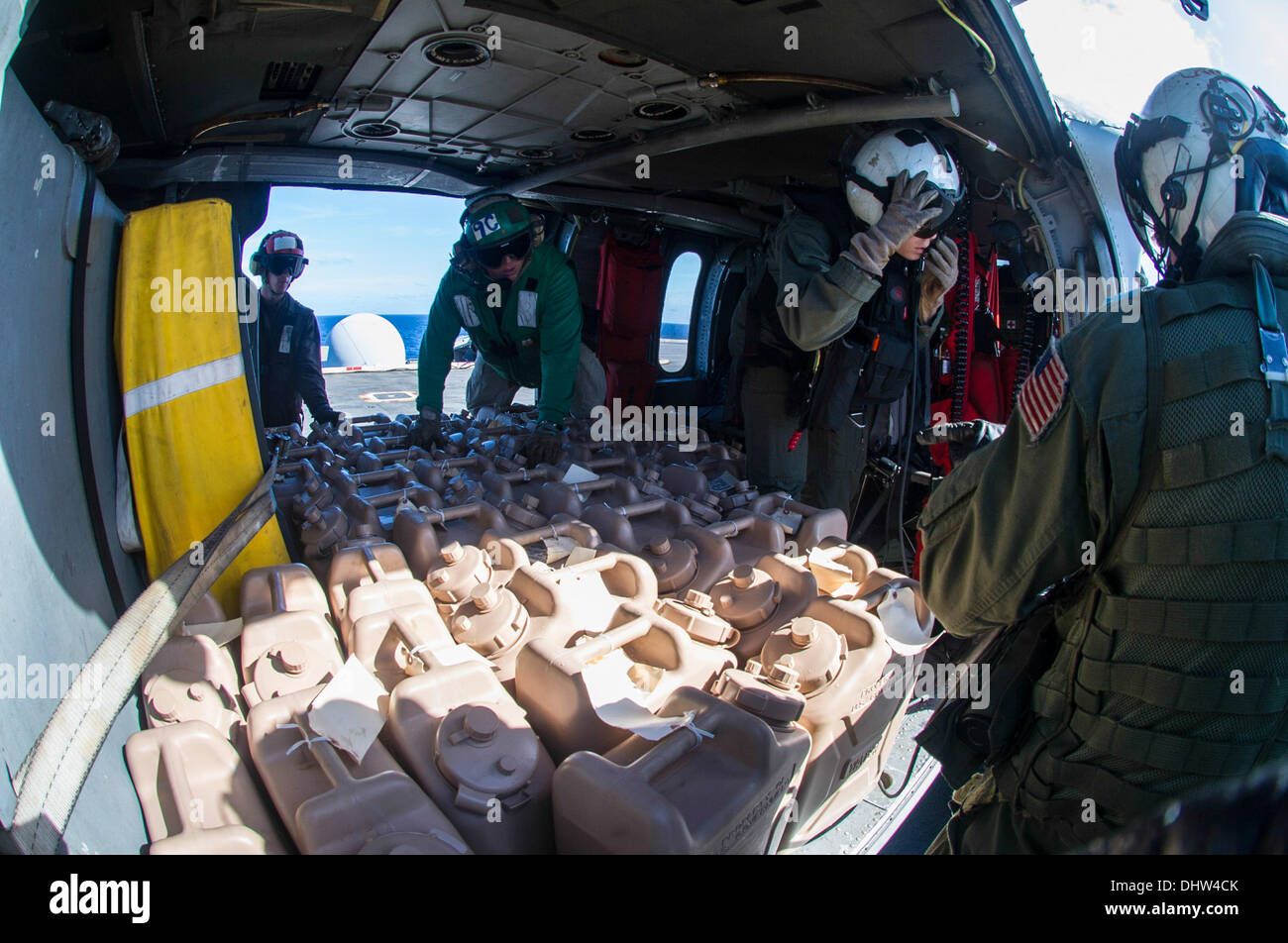 Seeleute an Bord der USS George Washington (CVN 73) laden während der Operation Damayan in der Philippinischen See am 15. November 2013 Wassercontainer auf einen Hubschrauber MH-60S Seahawk aus der Helicopter Sea Combat Squadron 12. Die Operation unterstützte Hilfsmaßnahmen nach dem Taifun Haiyan. Stockfoto