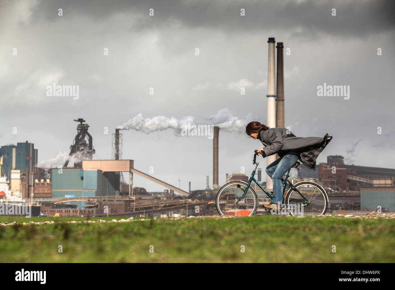 Holland, IJmuiden, Tata Steel Fabrik, Hochöfen. Radfahrer, Frau, versucht zu bleiben aufrecht in StoL Stockfoto