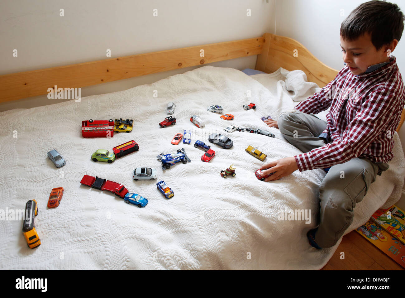 7-jähriger Junge spielt auf seinem Bett Stockfoto
