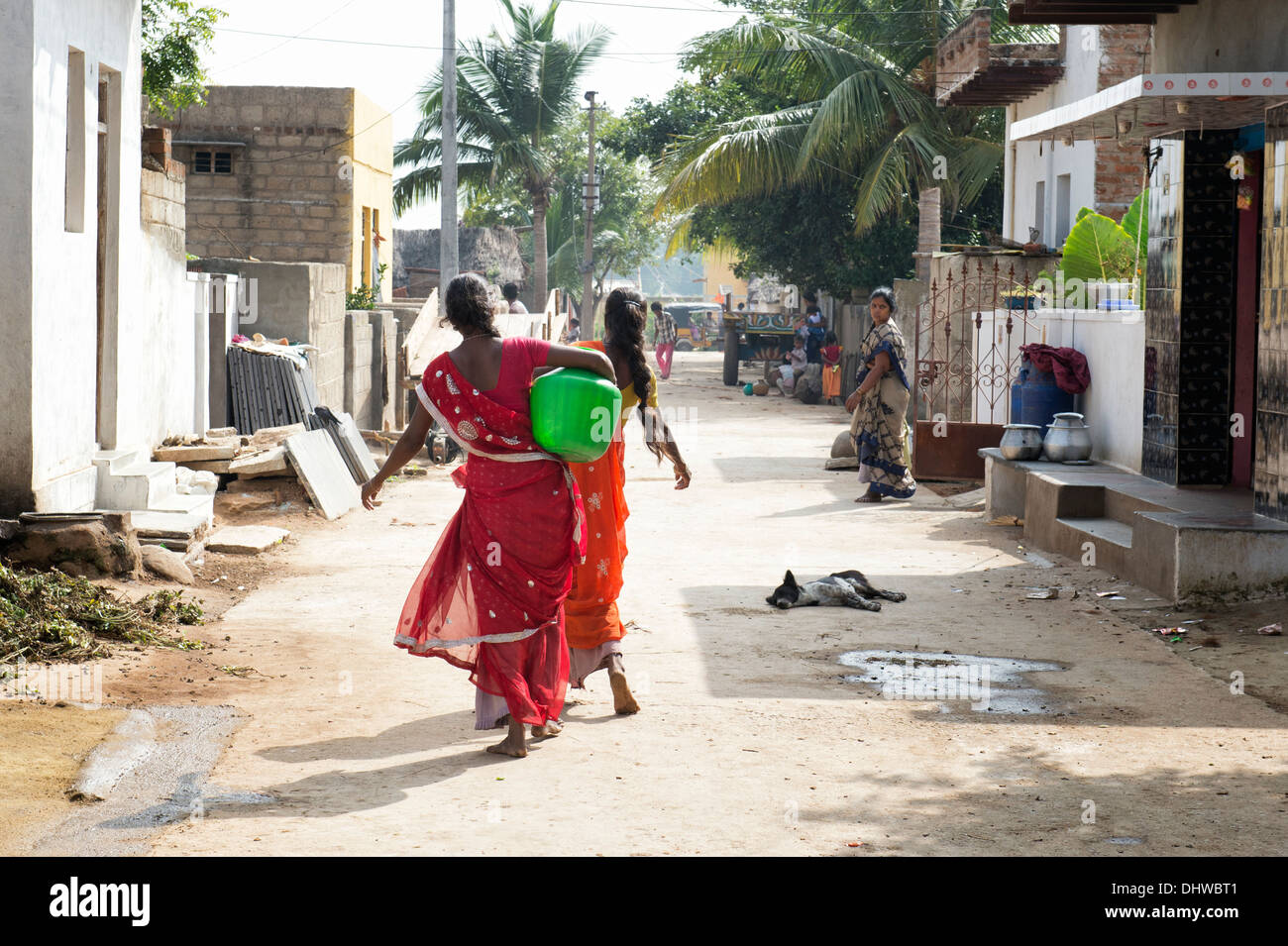 Indische Frauen tragen einen Plastiktopf mit Wasser aus einem Standrohr in einem indischen Dorf Straße. Andhra Pradesh, Indien Stockfoto