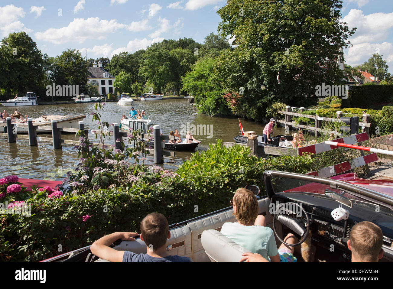 Niederlande, Loenen Aan de Vecht. Fluss Vecht. Jungs in alten altmodische Auto Blick auf Yachten im Fluss Stockfoto